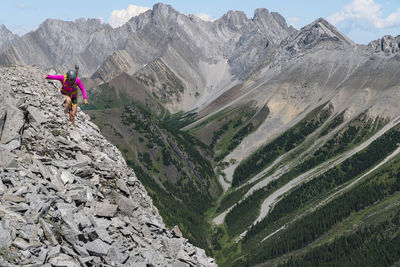 Female hiker scrambling along high ridge in kananaskis alberta