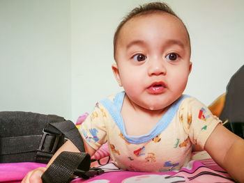 Cute baby girl drooling on bed at home