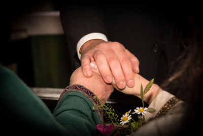 Cropped image of priest holding bride and groom hands during wedding ceremony