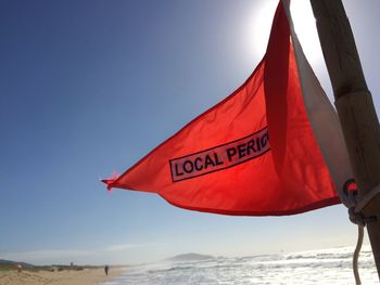 Red flag by sea against sky