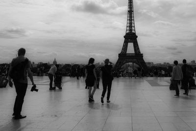 Tourists at eiffel tower against cloudy sky