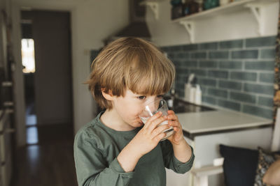 Boy in kitchen drinking milk