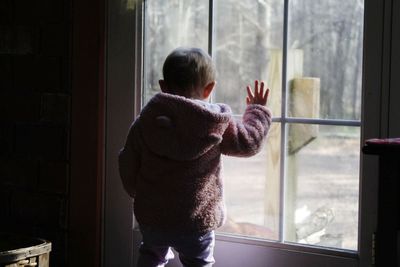 Rear view of girl looking through window