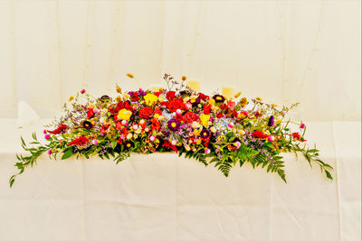 Colorful wedding floral arrangement against a pale white background