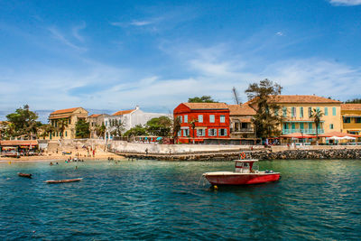 Boats in sea by buildings in city against sky