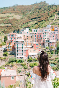 Rear view of woman standing against buildings in city