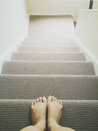 Low section of woman standing on steps at home