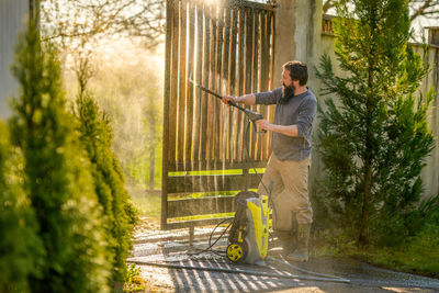 Full length of man washing gate