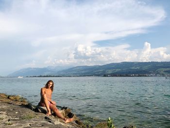 Full length of shirtless man in sea against sky