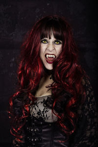 Portrait of woman with long hair wearing costume during halloween against black background