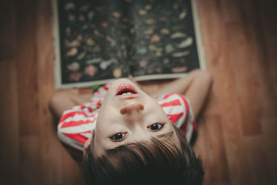 Close-up portrait of boy sitting by book at home