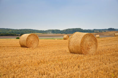 Hay bales on field against clear sky