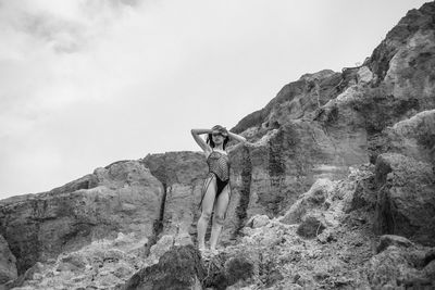 Man standing on rock by mountain against sky