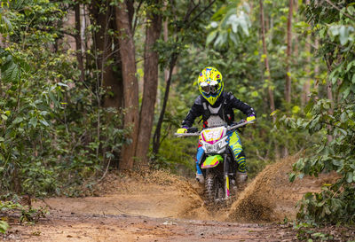 Woman riding her dirt-bike on forest track in pak chong / thailand