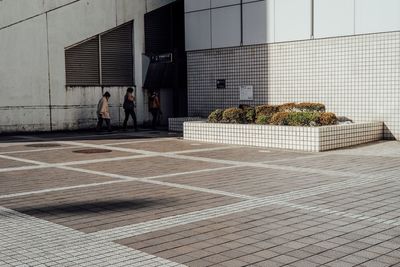 Men standing on sidewalk in city against sky