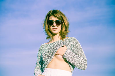 Portrait of seductive women covering breast while standing against sky