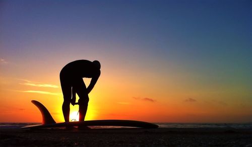 Silhouette of people standing on beach at sunset