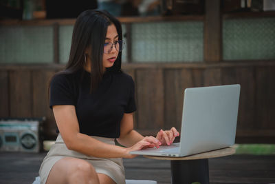 Woman using mobile phone while sitting on table