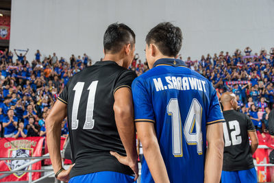 Men standing on soccer field against blue sky
