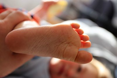 Cropped hand holding daughter leg at home