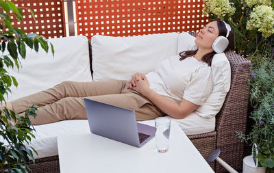 Midsection of woman using mobile phone while sitting on bed at home