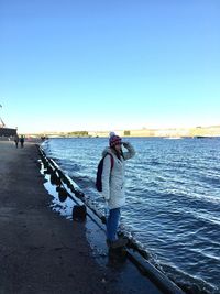 Woman photographing sea against clear sky