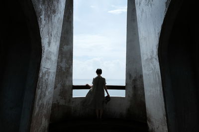 Rear view of man standing by building against sky