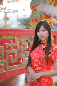 Portrait of smiling woman standing against red wall