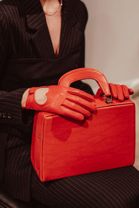 Female hands in a leather gloves holding a classic bright red handbag. fashion shot. vertical