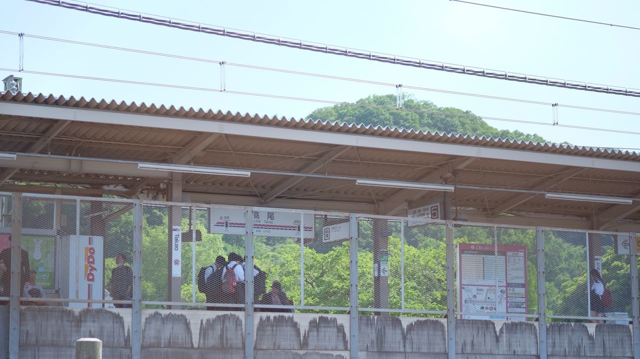 architecture, built structure, building exterior, graffiti, text, clear sky, low angle view, western script, day, sky, outdoors, wall - building feature, rail transportation, no people, plant, communication, railing, cable, power line, connection