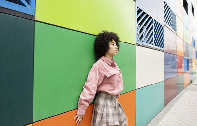 Young woman leaning on colorful wall