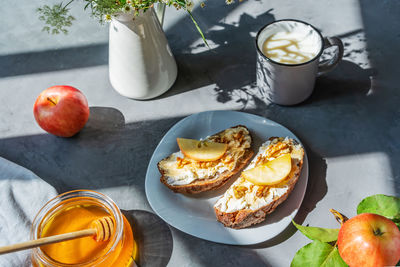 Bread slices with cottage cheese, honey, apples and nuts on the plate. breakfast concept