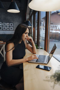 Young woman using laptop on table in cafe