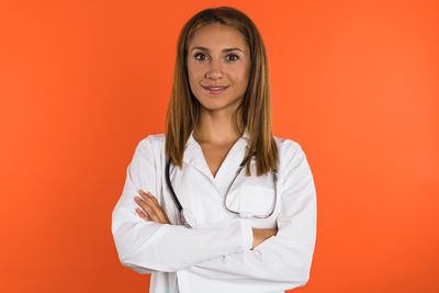 Portrait of young woman standing against yellow background