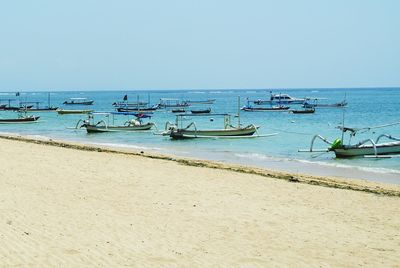 Boats in sea against clear blue sky