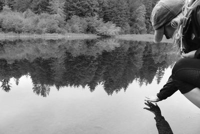 Woman touching water in calm lake