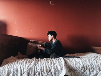 Young man sitting on bed at home