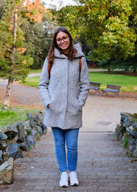 Portrait of young woman standing on footpath