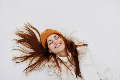 Happy young woman with eyes closed lying on snow