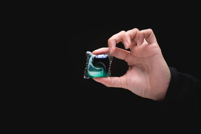 Close-up of hand holding electronic cigarette against black background