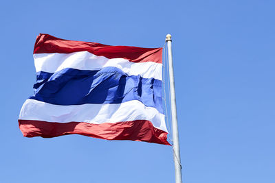 Low angle view of flags flag against blue sky