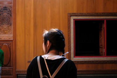 Rear view of woman standing by building