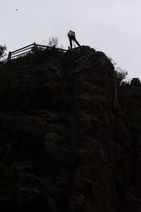 Low angle view of man on rock against sky