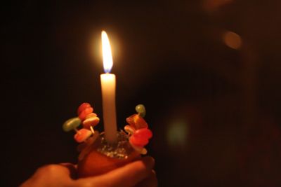 Close-up of illuminated candle holding candles in darkroom