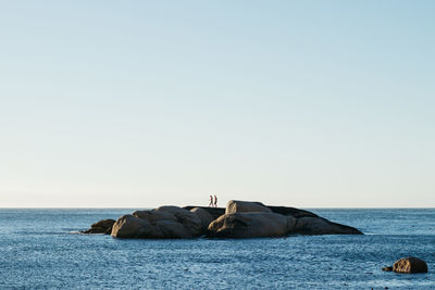 Rocks on sea against clear sky