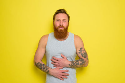 Portrait of man standing against yellow background