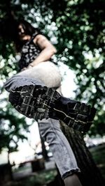 Low section of boy with plants against trees