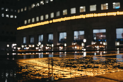 Reflection of illuminated building on wet glass at night