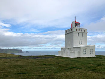 Lighthouse on beach against sky