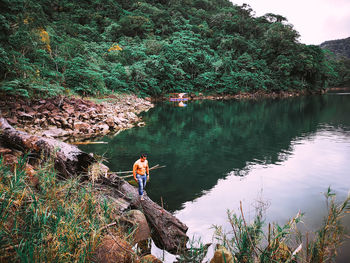 Woman on rock by lake in forest